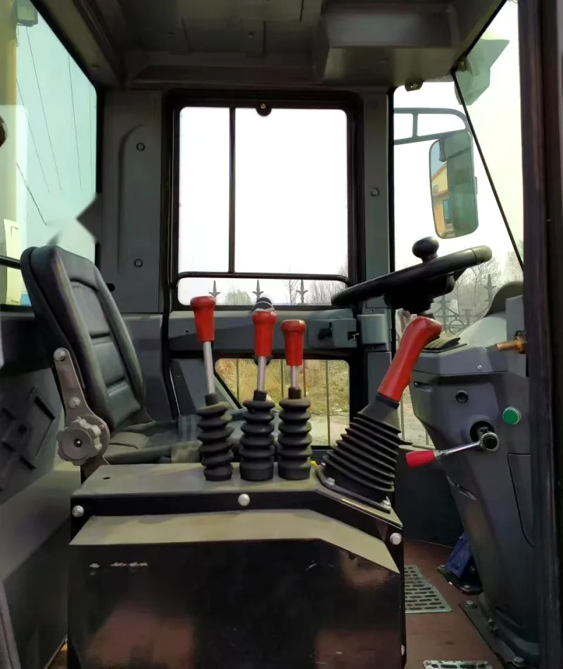Cab interior of a self-loading concrete mixer with three control levers, steering column and suspension seat