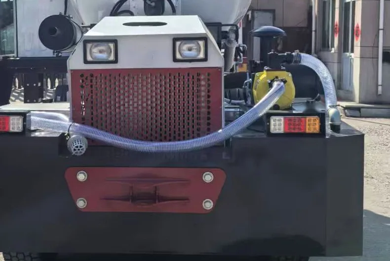 Rear of a self-loading mixer showing radiator grille, lamps and an external water pump with suction hose