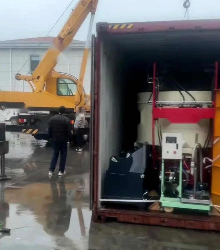Container being loaded in the rain beside a mobile crane, with a control cabinet and ancillary plant already inside