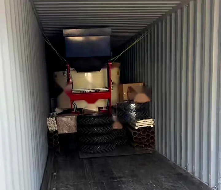 Interior of a loaded shipping container: machine lashed with webbing, spare tyres, steel pipe and cartons packed around it
