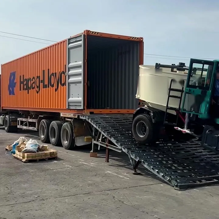 Self-loading concrete mixer climbing steel ramps into a 40-foot shipping container on a trailer